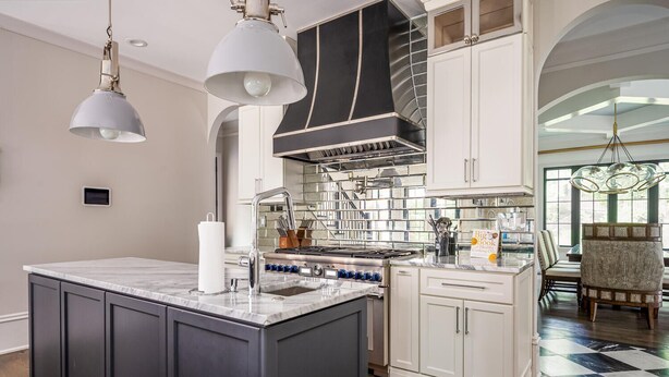 A modern kitchen with a central island, stainless steel appliances, and a chandelier.