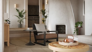 A modern living room with a fireplace, a round wooden table, a sofa, and a chair.