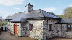 A stone house with a tiled roof, a wooden door, and a small window.