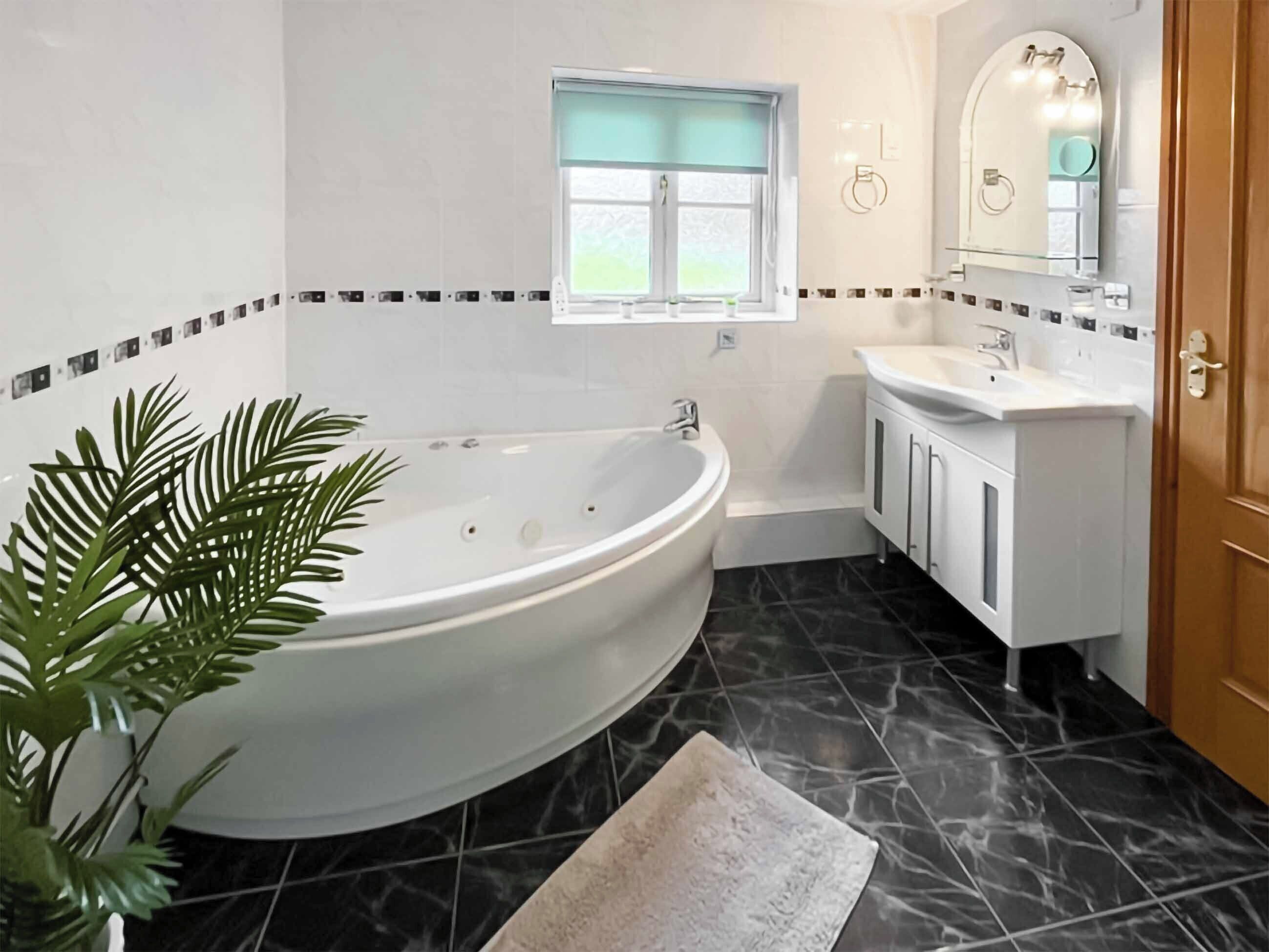 Une salle de bain avec une baignoire sur pieds, une petite fenêtre, un lavabo et un miroir.