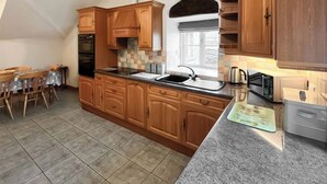 A kitchen with wooden cabinets, a granite countertop, a built-in oven, and a window with a view.