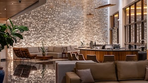 A modern interior with a stone wall, a bar area, and seating arrangements. - Vert Hotel Spa (Itatiaia)