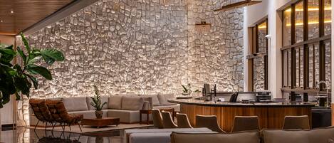 Un interior moderno con una pared de piedra, una zona de bar y diferentes disposiciones de asientos.