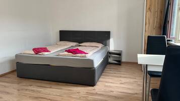 Un dormitorio moderno con cama, mesitas de noche y escritorio.