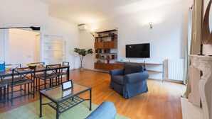 A modern living room with a sofa, a glass coffee table, and a dining area with chairs and a table.