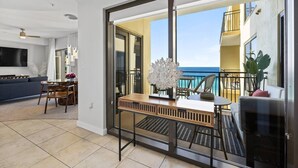 A modern living room with a large sliding glass door leading to a balcony with a view of the ocean. - Luxury Gulf View Suite with Penthouse Views! (Panama City Beach)