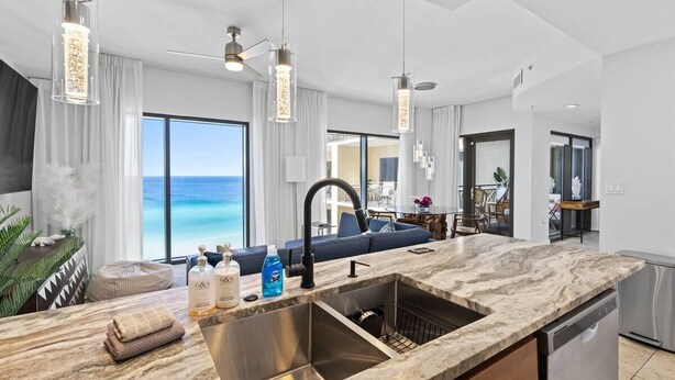 A modern kitchen with a large island, stainless steel sink, and pendant lighting. - Luxury Gulf View Suite with Penthouse Views! (Panama City Beach)