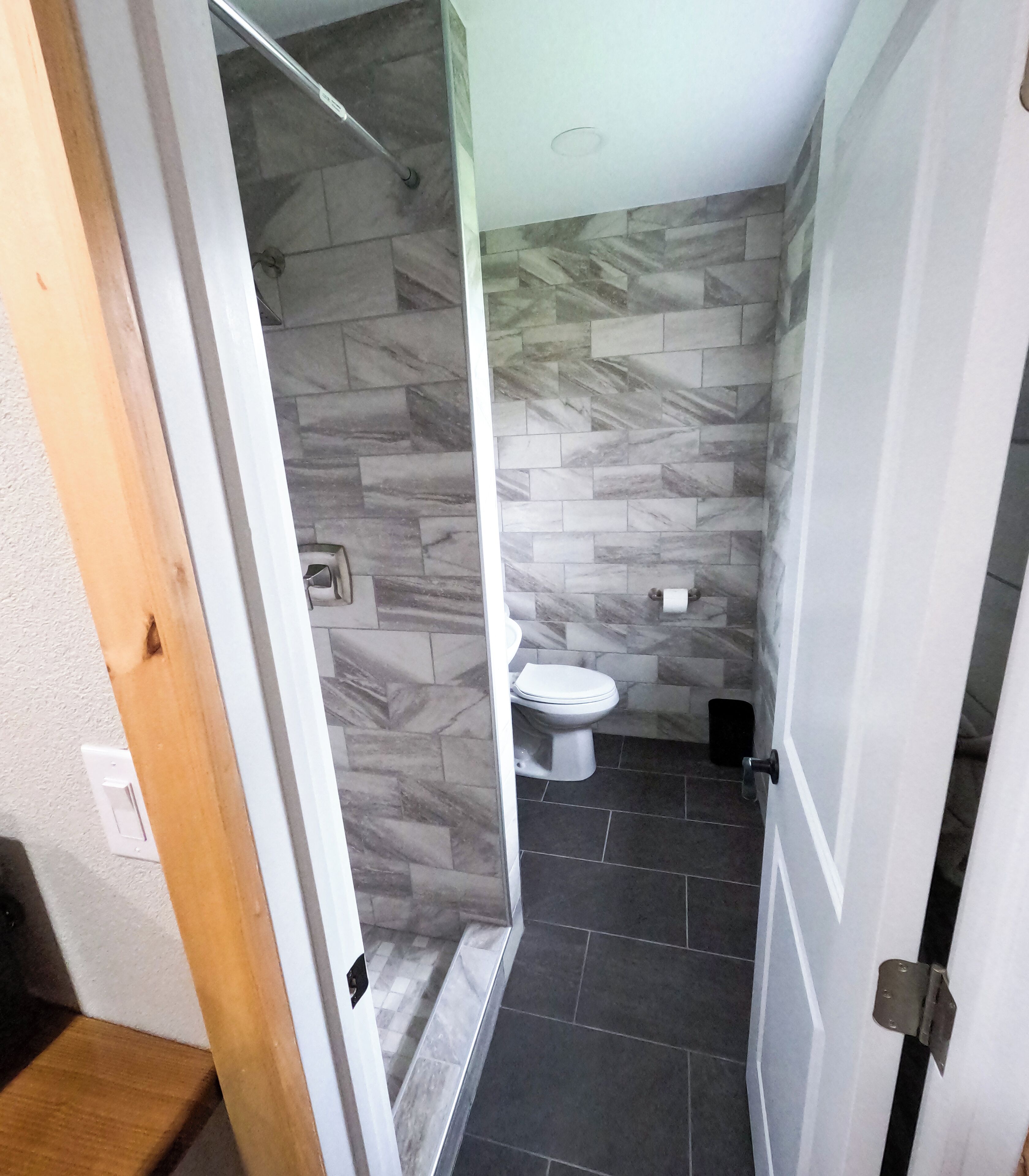 A bathroom with a toilet, a shower, and a tiled floor.