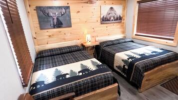 Una habitación con dos camas, un banco, paredes de madera y luces en el techo.