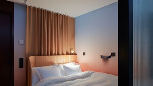 A hotel room with a bed, curtains, a headboard, and a wall-mounted light fixture. - Zzz Dreamscape Hotel - Self Check-In & Digital Key (Stockholm)