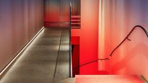 A narrow hallway with a textured ceiling, a red-lit area, and a glass partition. - Zzz Dreamscape Hotel - Self Check-In & Digital Key (Stockholm)