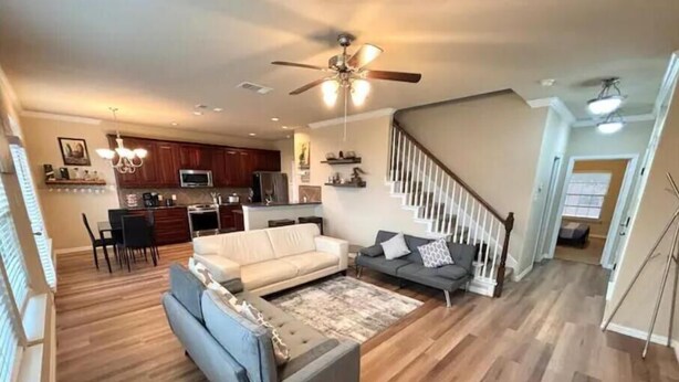 A spacious living room with a sofa, a coffee table, and a staircase leading to the upper floor.