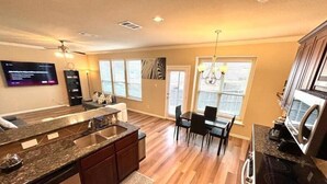 A modern kitchen with a central island, built-in appliances, and a dining area with a chandelier.