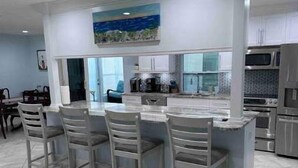 Uma cozinha moderna com uma ilha central, banquetas e eletrodomésticos embutidos.