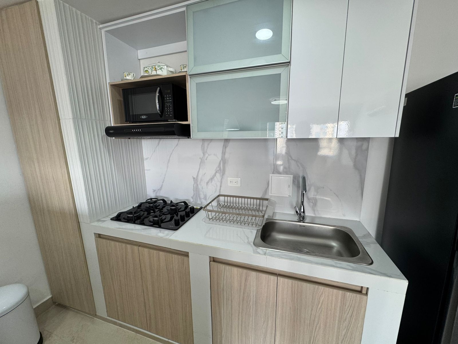 A compact kitchen with a gas stove, a sink, and a microwave.