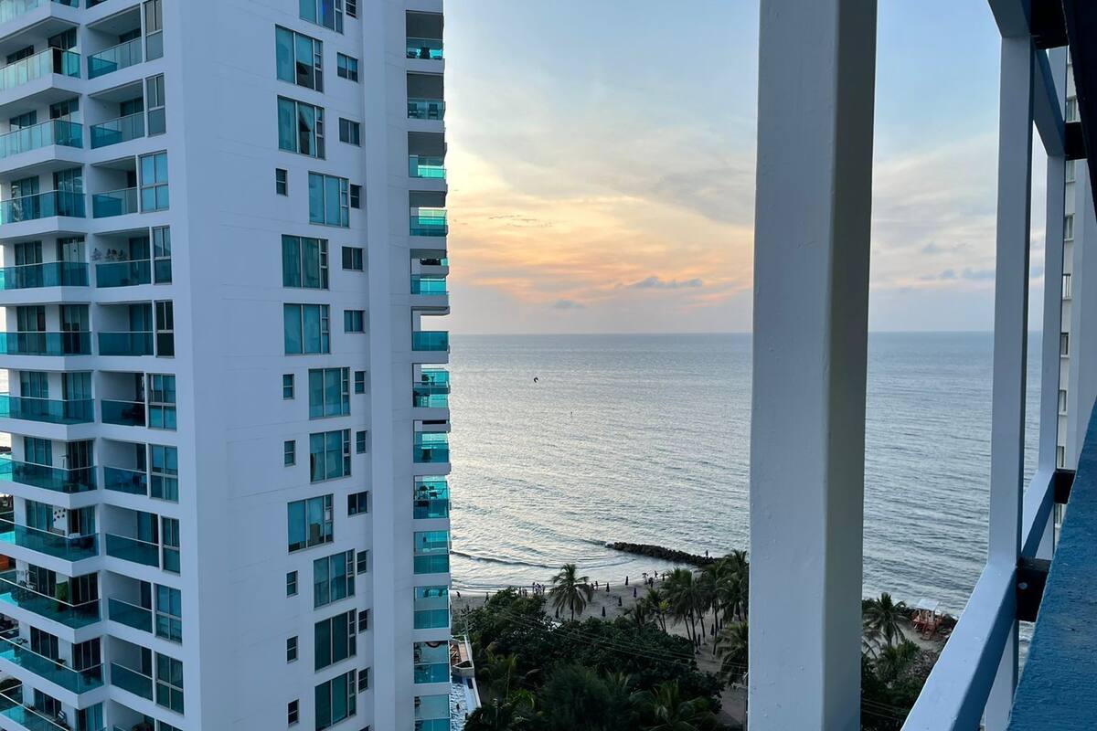 A high-rise building with multiple balconies overlooking a beach.