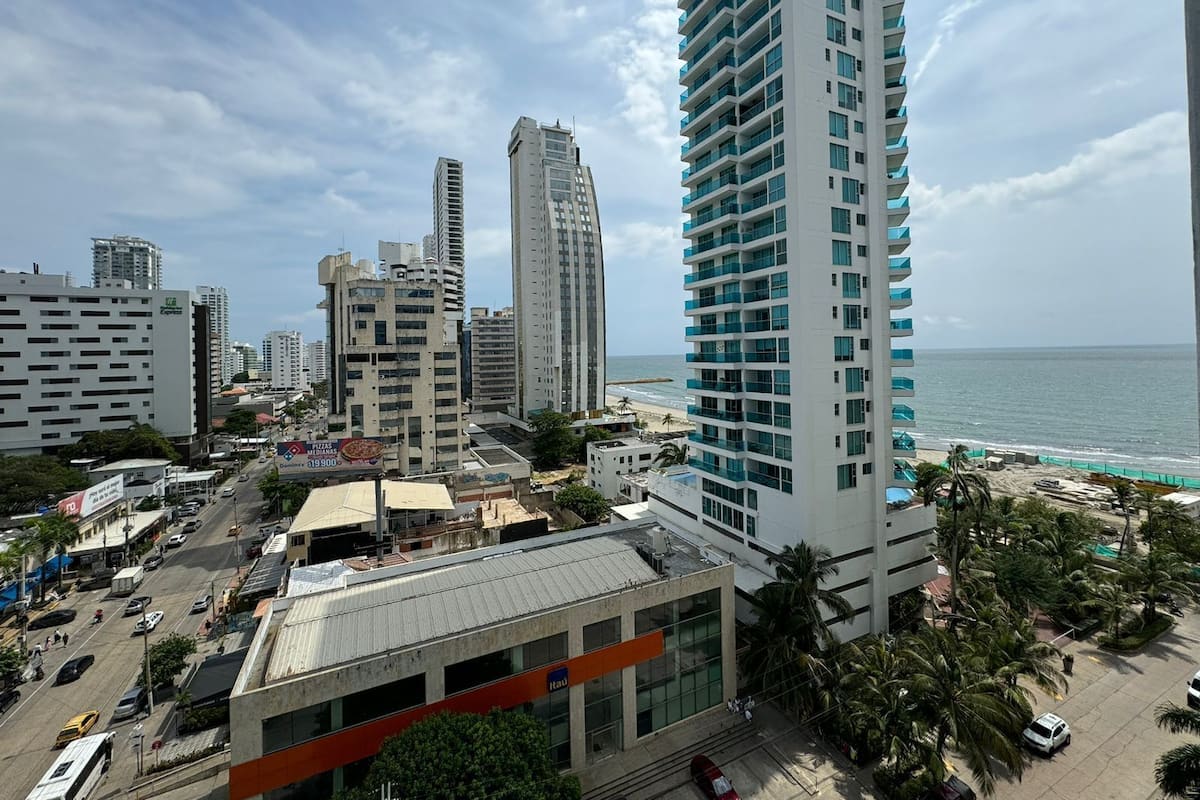 A high-rise hotel with a view of the beach, featuring multiple floors, balconies, and a modern architectural design.