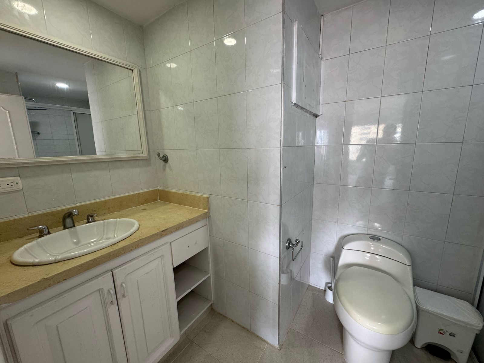 A bathroom with a sink, mirror, toilet, and shower.