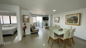 A modern living room with a dining area, a sofa, a TV, and artwork on the walls. - Apartamentos en Edificio Portofino ICDI (Cartagena)