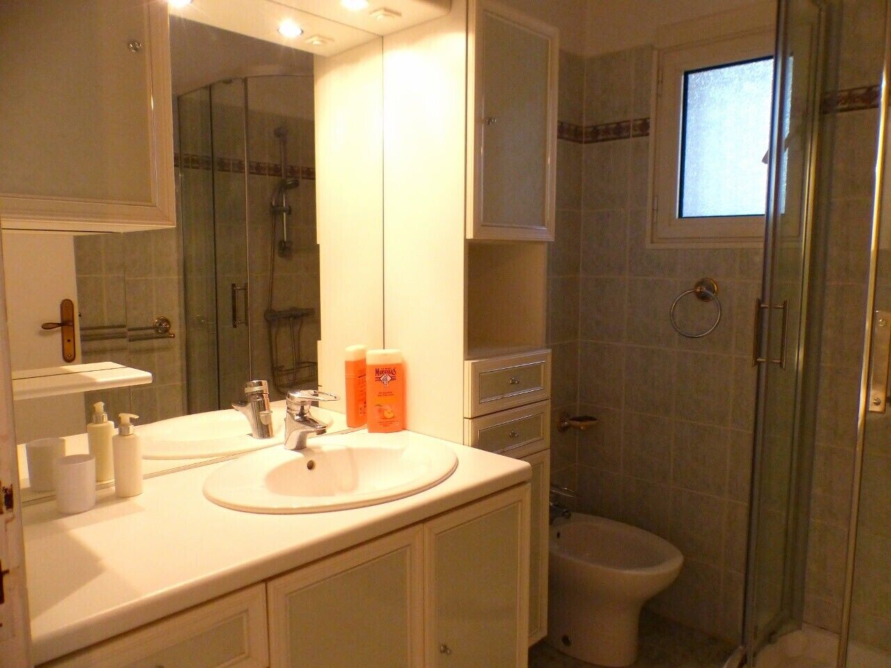 Un baño con lavamanos, espejo y ducha.