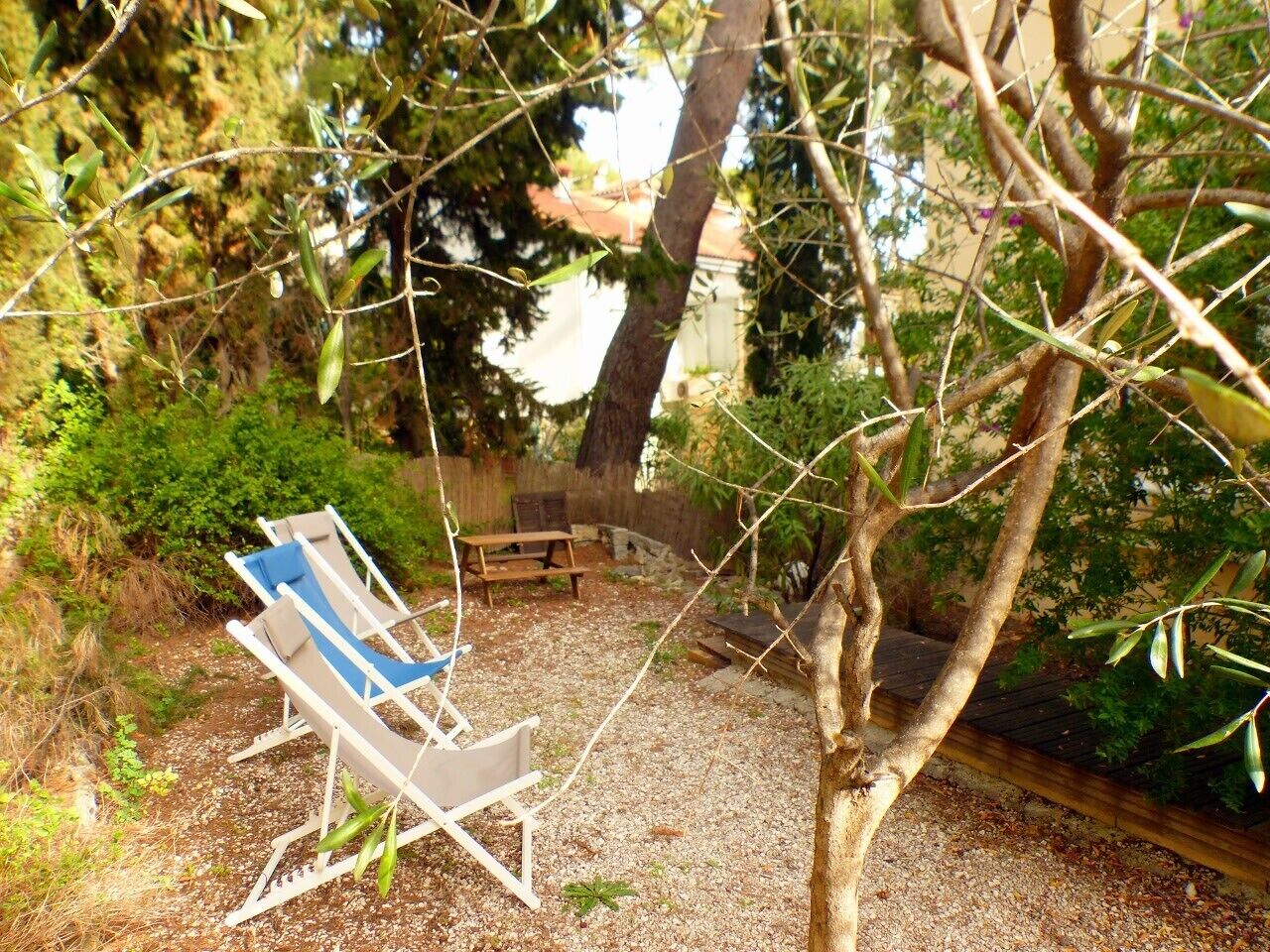 Ein Garten mit einer Holzdiele, einem blauen und weißen Liegestuhl und einem kleinen Holztisch.