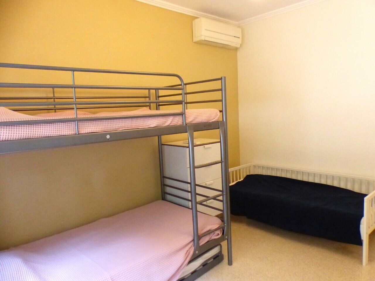 Habitación con literas, un radiador y pared blanca.