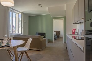 Una sala de estar moderna con un sofá, una mesa de comedor con sillas y una zona de cocina con mostrador y armarios.