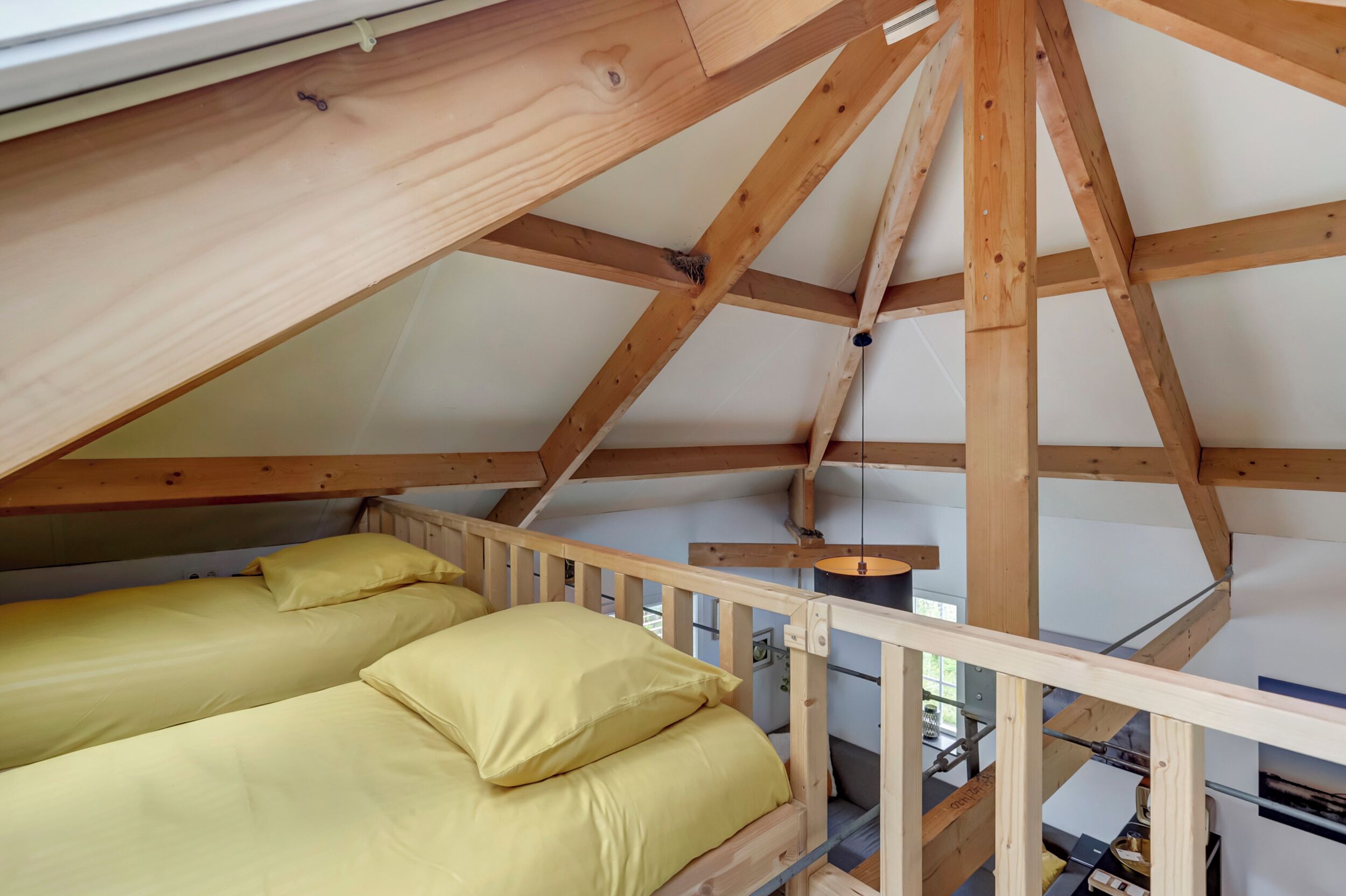 Een slaapzaal met houten balken, stapelbedden en een klein tafeltje.