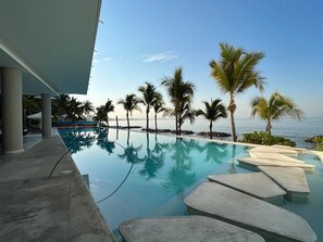 A pool with clear water, palm trees, and a view of the sea. - Park Life Narval (Bucerías)