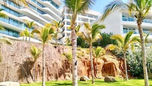 Hotel com design moderno, apresentando paisagem rochosa e palmeiras.