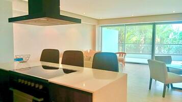 Una cocina moderna con una isla central, estufa y un amplio ventanal con vistas a zonas verdes.