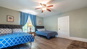 A bedroom with two beds, a ceiling fan, and a door.