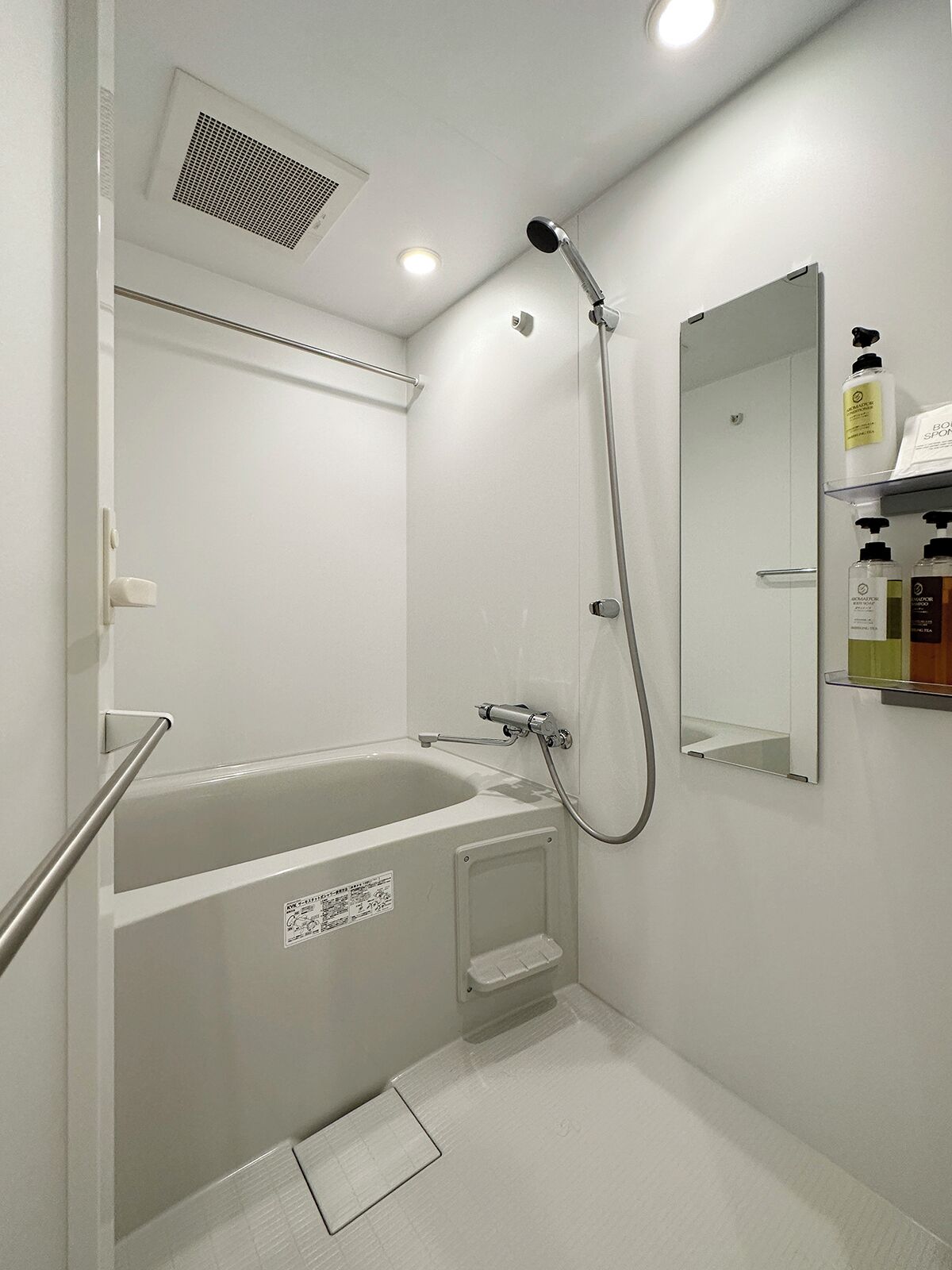 A modern bathroom with a bathtub, a shower, and a mirror.