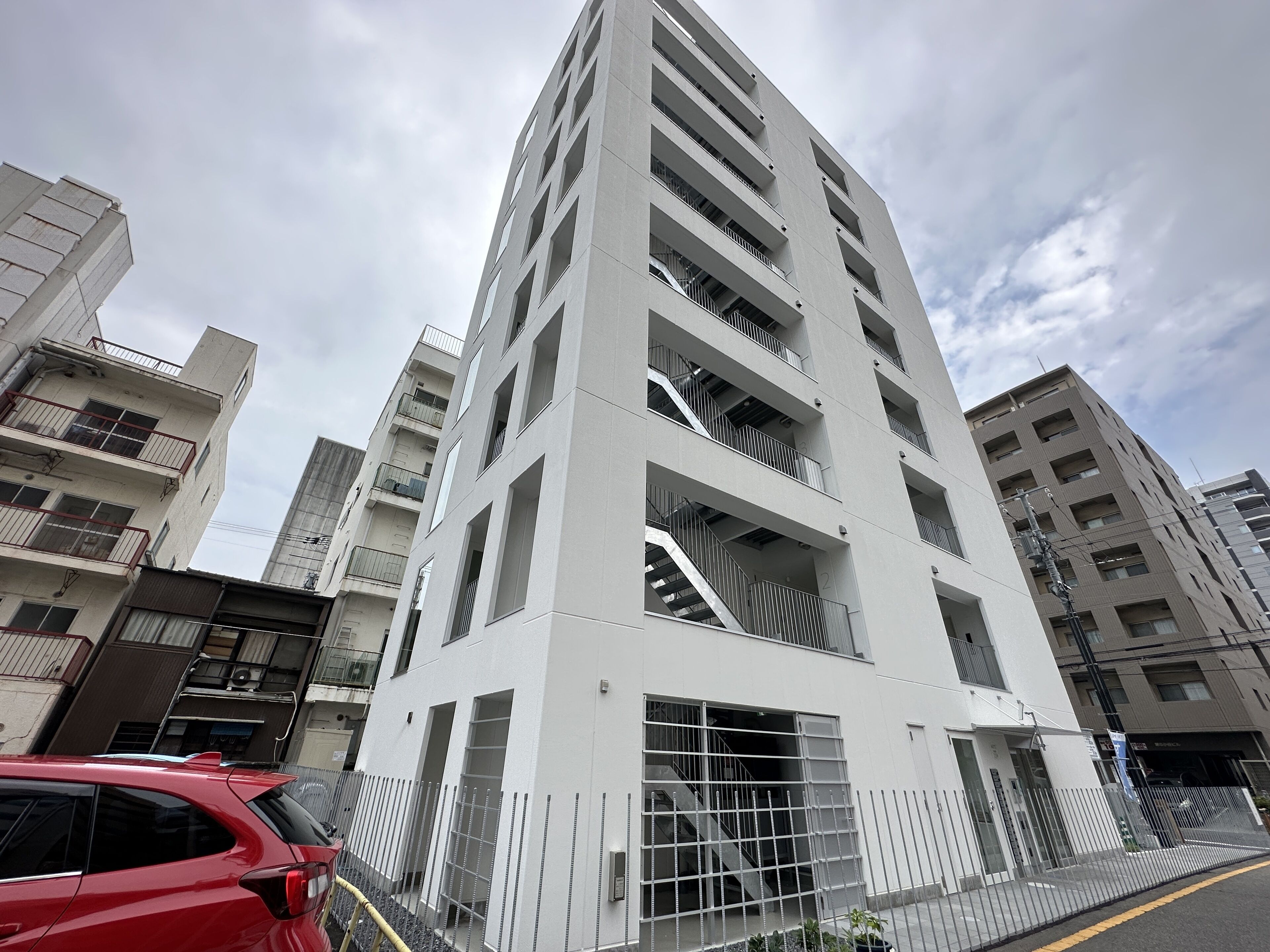 Un edificio de varias plantas con diseño arquitectónico moderno, con balcones y una escalera central.