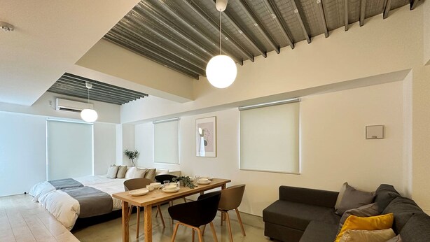 A modern, well-lit living room with a dining area, a sofa, and a bed. - Arts Dobashi (Hiroshima)