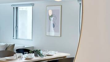 A modern dining area with a wooden table, black and grey chairs, and a hanging light fixture.