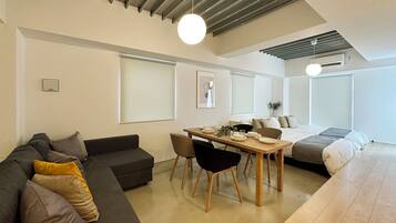 A modern, well-lit living area with a sofa, dining table, and a bed.