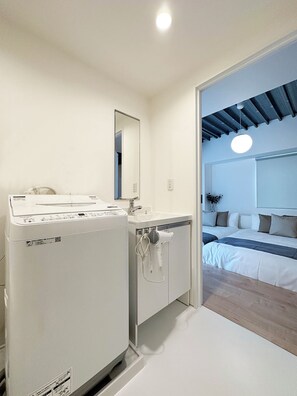 A modern bathroom with a white washing machine, a sink, and a mirror. - Arts Dobashi (Hiroshima)
