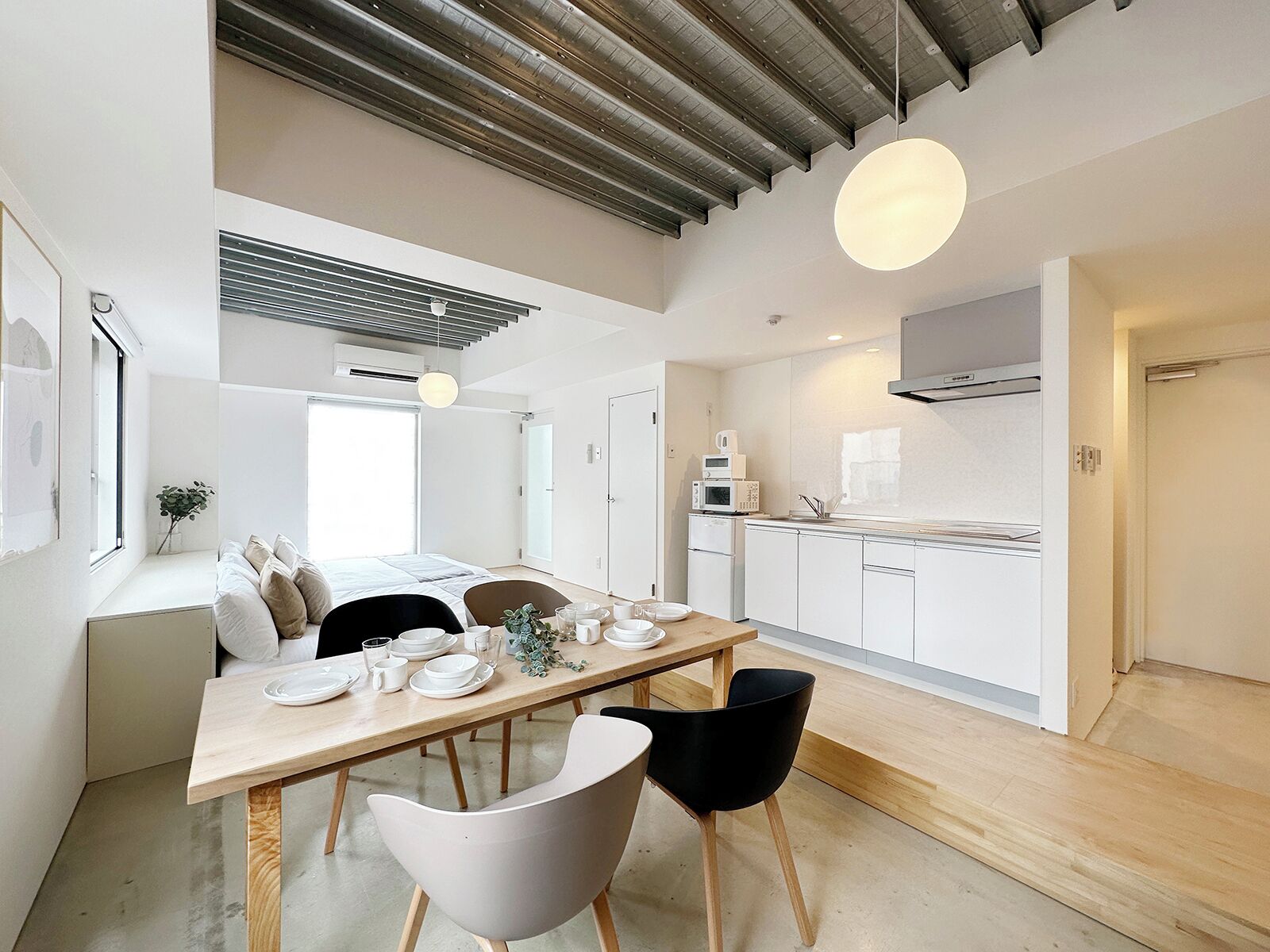 Une cuisine moderne avec des meubles blancs, une table à manger en bois et des chaises noires.