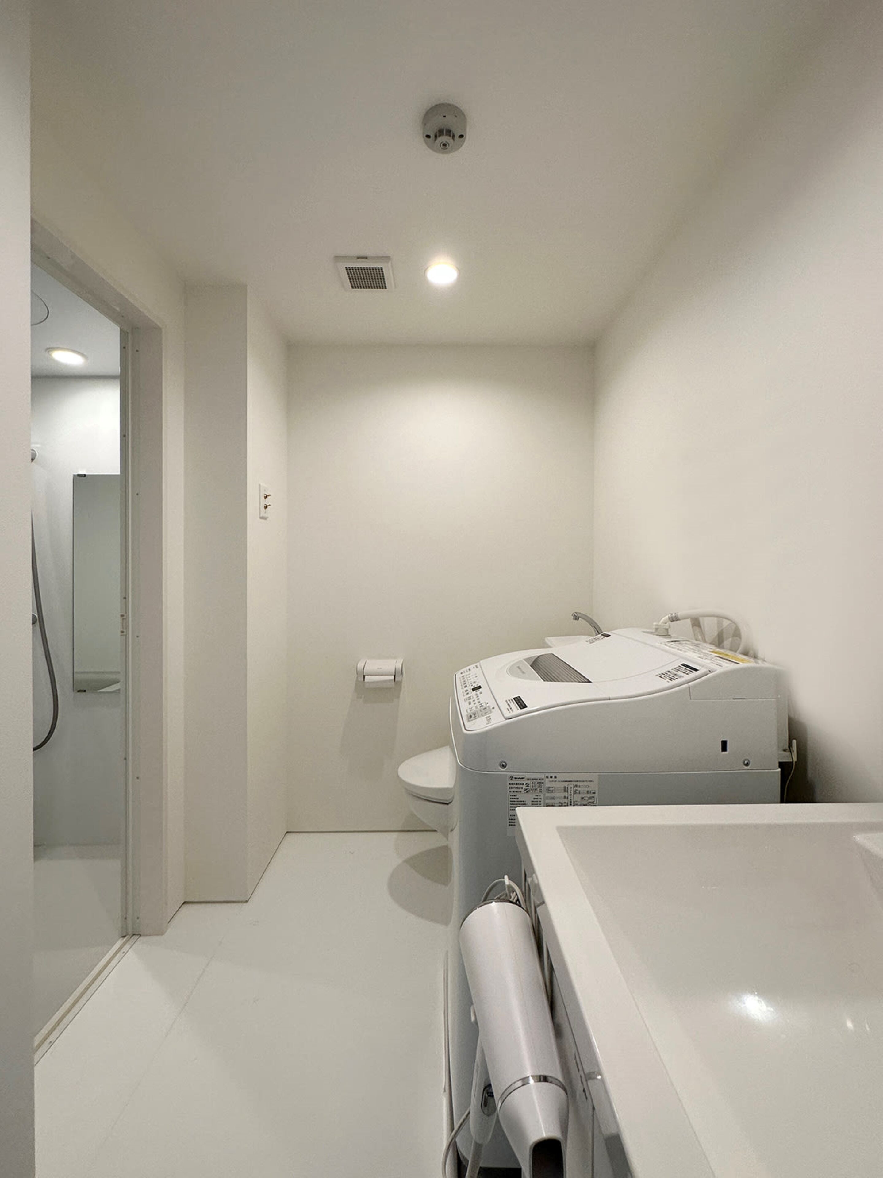Une petite salle de bain moderne équipée de toilettes, d’une douche et d’un grand radiateur blanc.