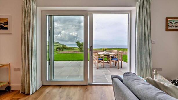 Una habitación con puerta corrediza de vidrio que da a un patio exterior con mesa y sillas.