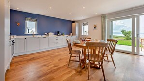 Una cocina moderna con armarios blancos, una pared de acento azul y un comedor con sillas de madera y una mesa.