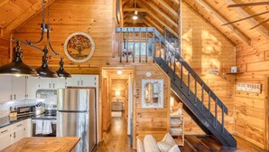 A cozy cabin with a kitchen, dining area, and a staircase leading to a loft. - 2 King BR with Loft, Mountain Views & Hot Tub (Blue Ridge)