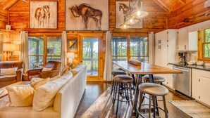 A rustic cabin interior with a wooden dining area, a sofa, and a kitchen with a coffee maker. - 2 King BR with Loft, Mountain Views & Hot Tub (Blue Ridge)