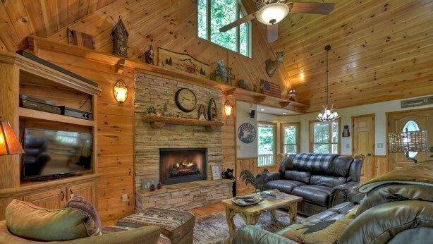 L’intérieur chaleureux d’un chalet en rondins, avec une cheminée en pierre, des meubles en cuir et des murs en bois.