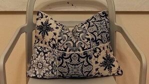 A chair with a patterned cushion against a wall with abstract black and white artwork.