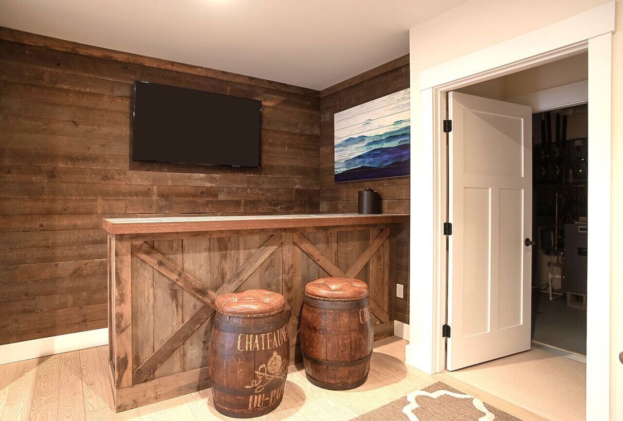 Een rustiek interieur met een houten wand, een tv aan de muur en twee houten vaten.