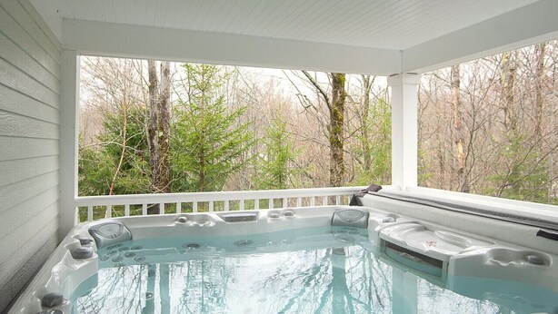Ein Whirlpool auf einer überdachten Veranda mit Blick auf Bäume.