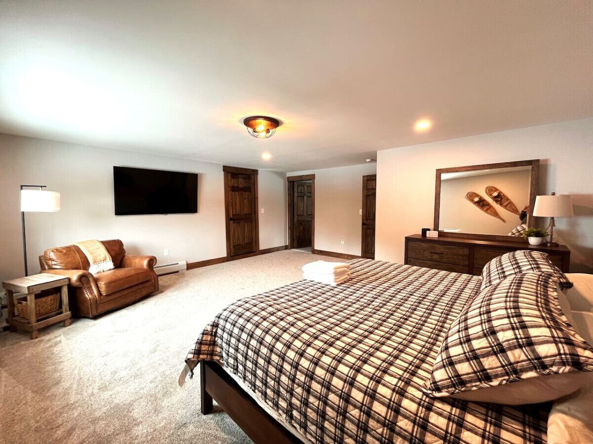 Ein Schlafzimmer mit einem großen Bett, einem Fernseher, einer Couch und einem Schreibtisch.
