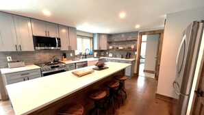 Una cocina moderna con una isla grande, taburetes de bar, electrodomésticos de acero inoxidable y vistas al comedor.